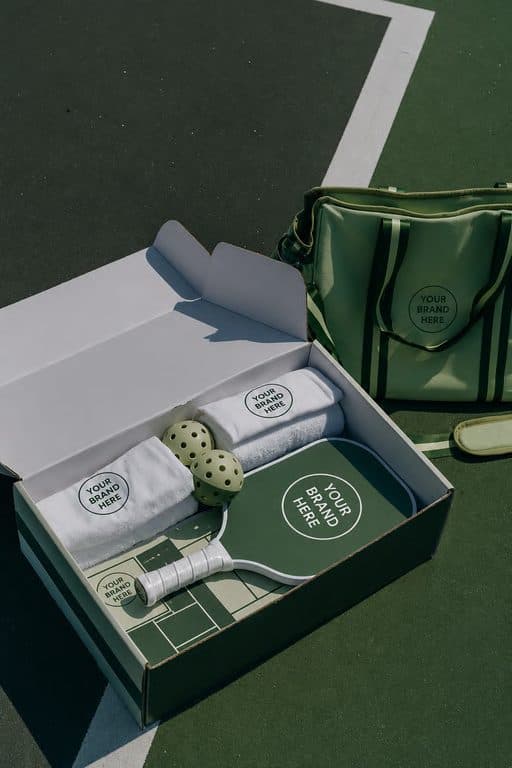 An open welcome box with a racket, towel and branded accessories