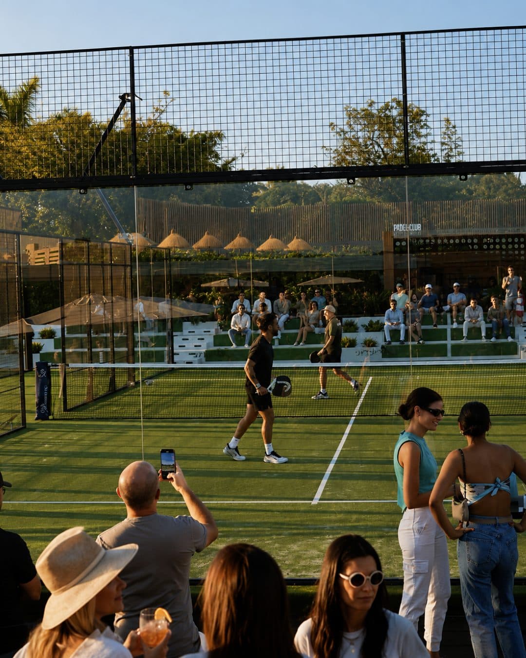 Guests watching a padel match at golden hour